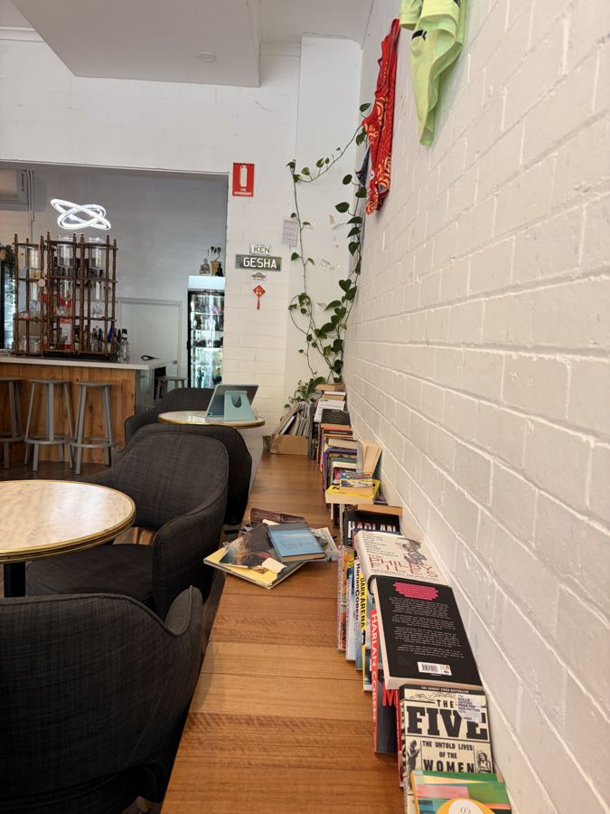 A café with a wall of books and a window bench.